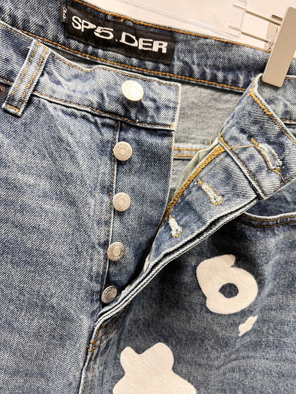 Light blue denim pants with button fly and white graphic patch detail