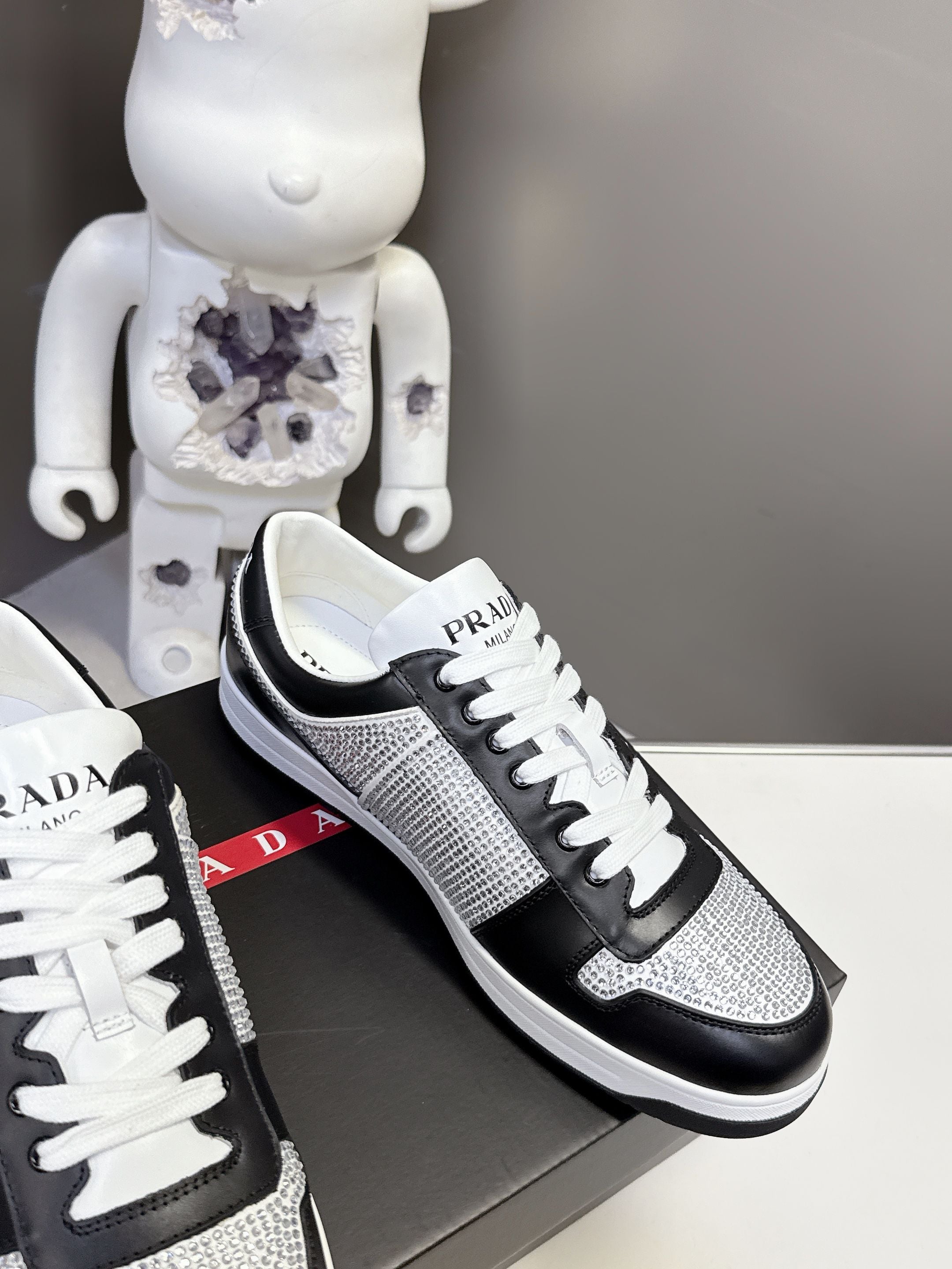 Black and silver low-top sneakers with white laces and Prada side label