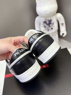 Black low-top sneakers with white platform sole and Prada logo heel tab