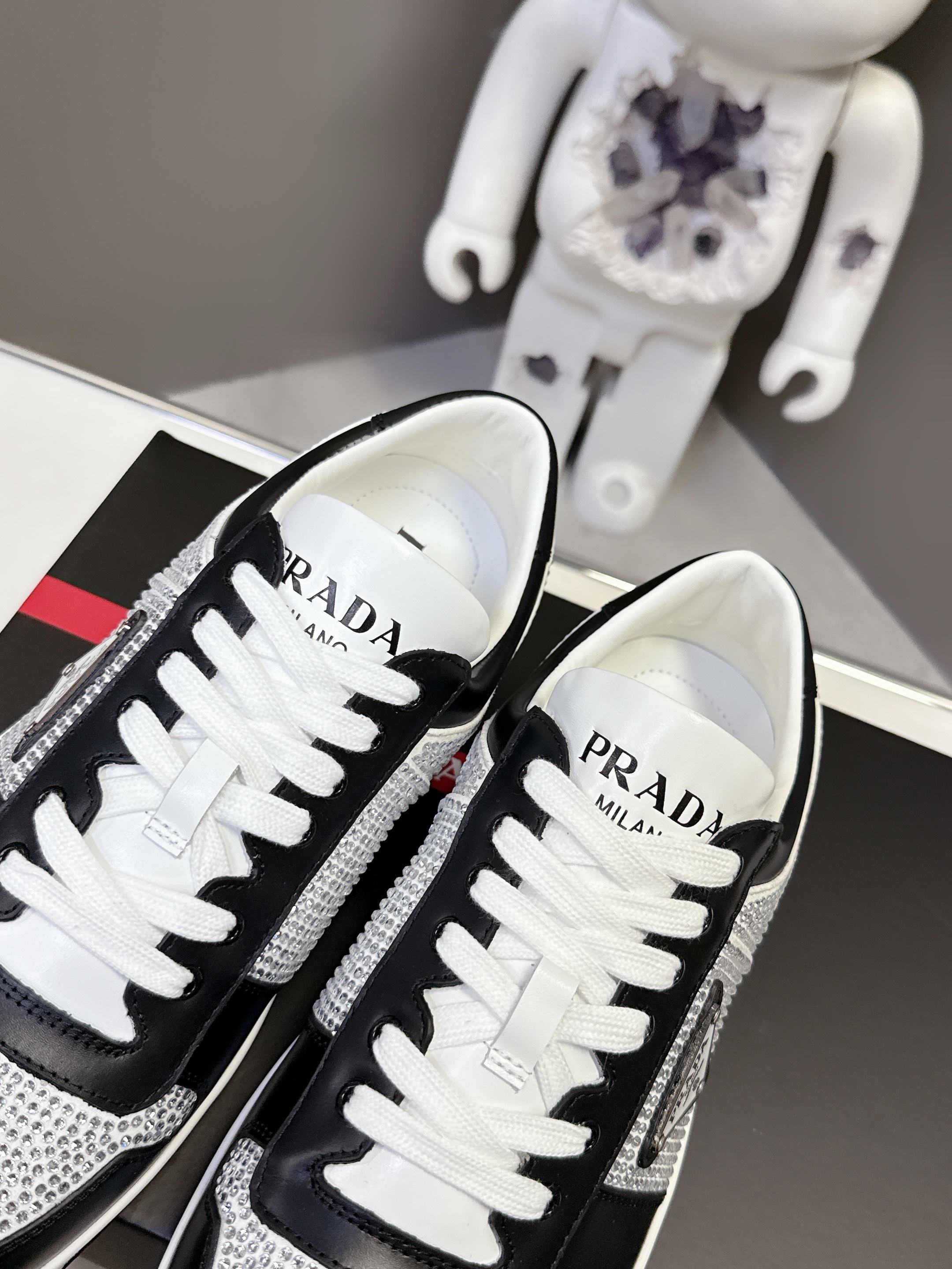 Black low-top sneakers with white laces, Prada logo on inner lining