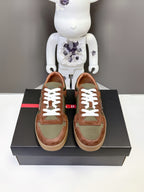 Pair of unisex sneakers in brown and olive with white lace-up front on display