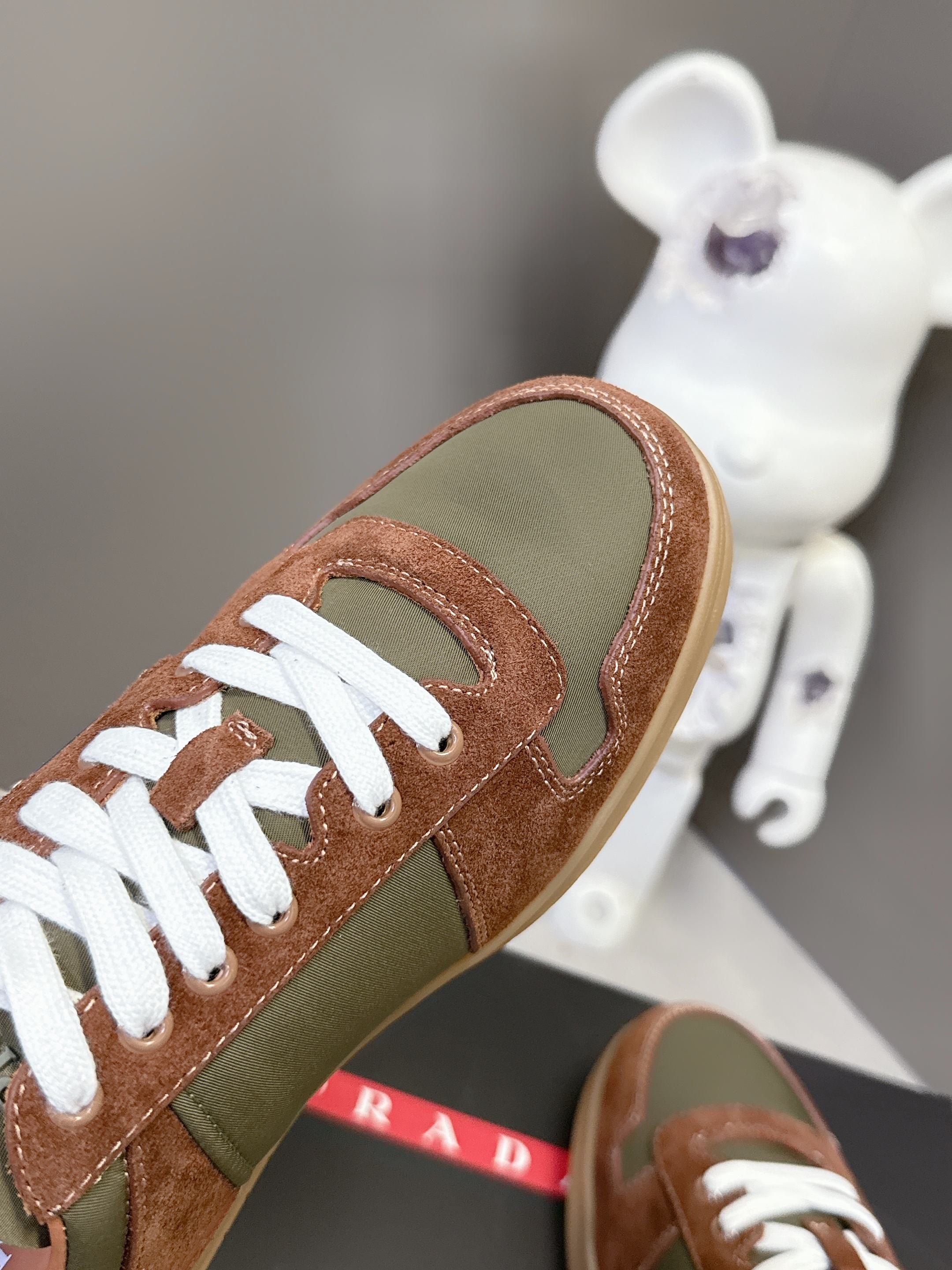 Unisex sneakers close-up: brown suede toe, olive side panel, white laces