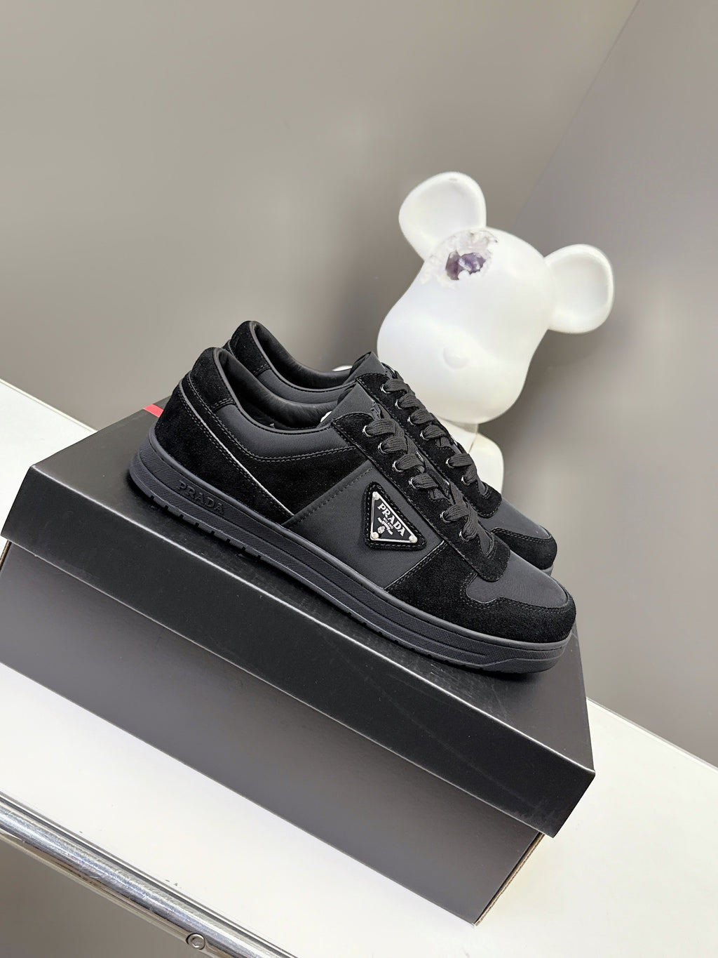 Black Prada unisex sneakers with lace-up front and triangular logo patch on shoebox