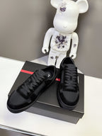 Black Prada unisex sneakers set on shoebox, featuring lace-up front and side logo patch