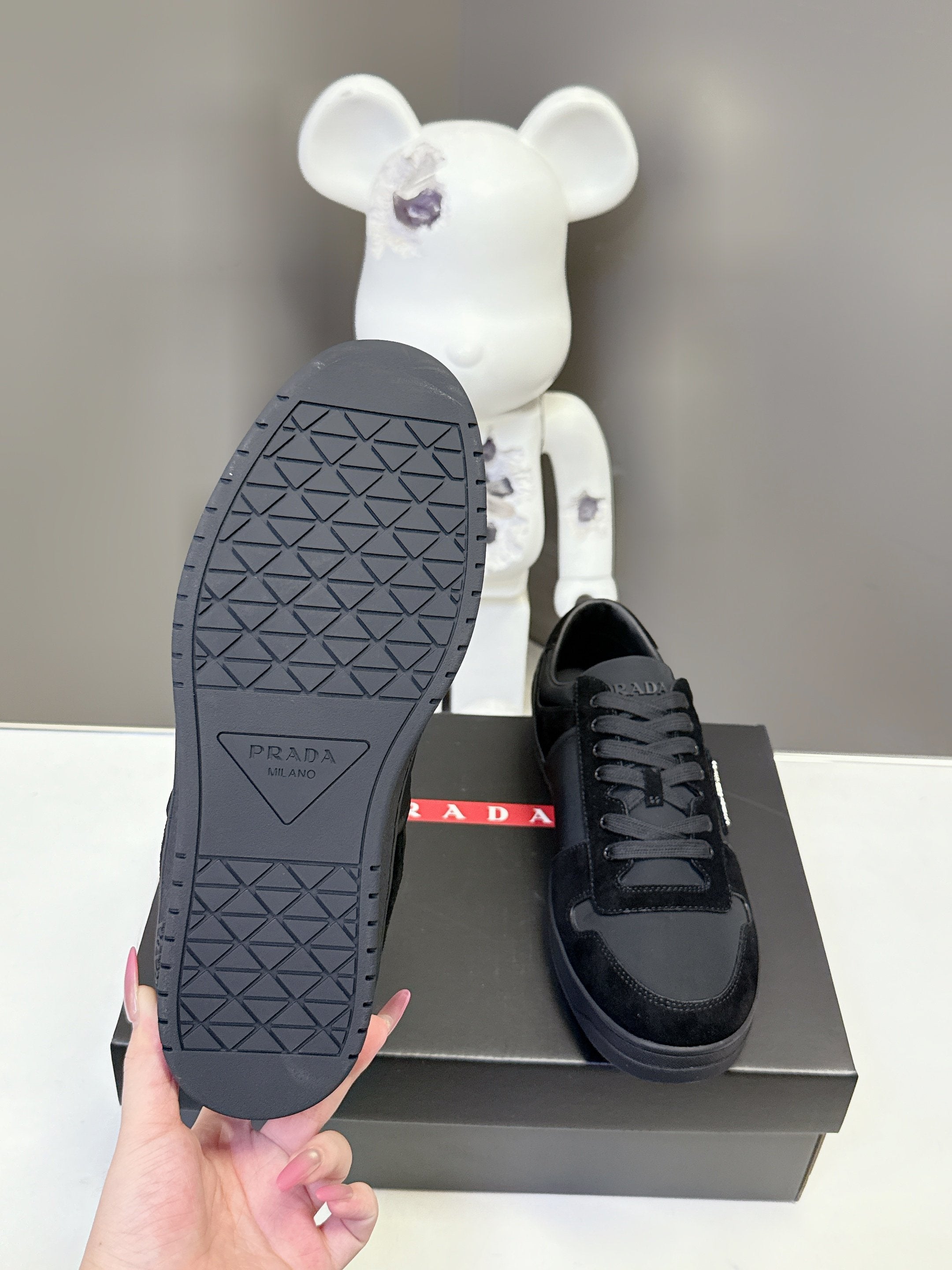 Black Prada unisex sneakers sole view with textured tread pattern on shoebox