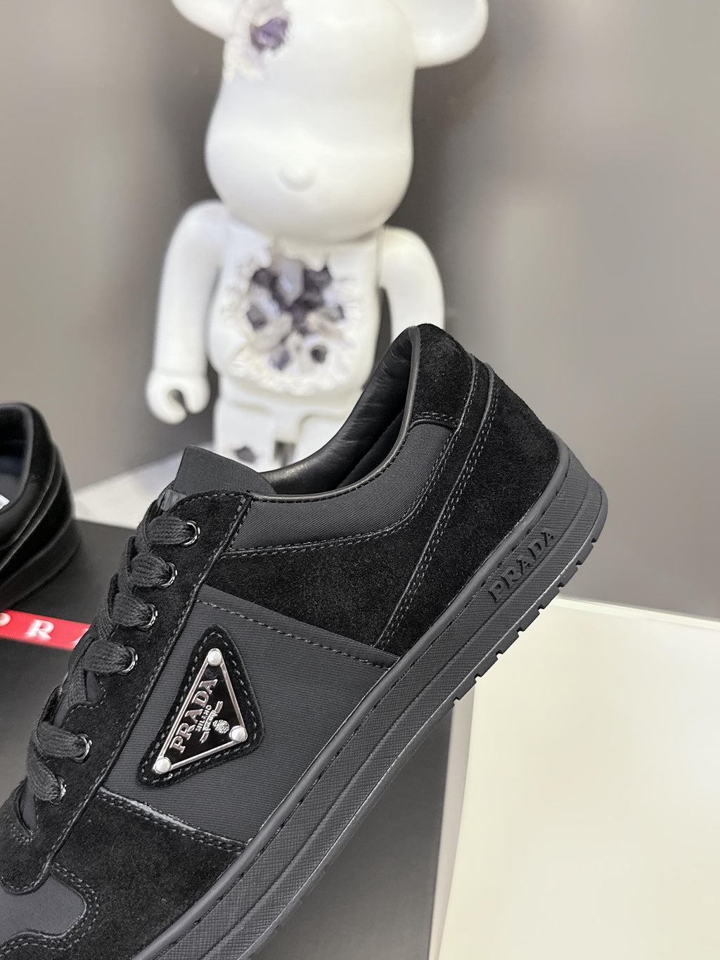 Black Prada unisex sneaker angled view with triangular logo patch and stitched seams