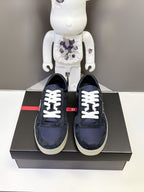 Prada unisex sneakers pair, navy suede with white lace-up front on black box
