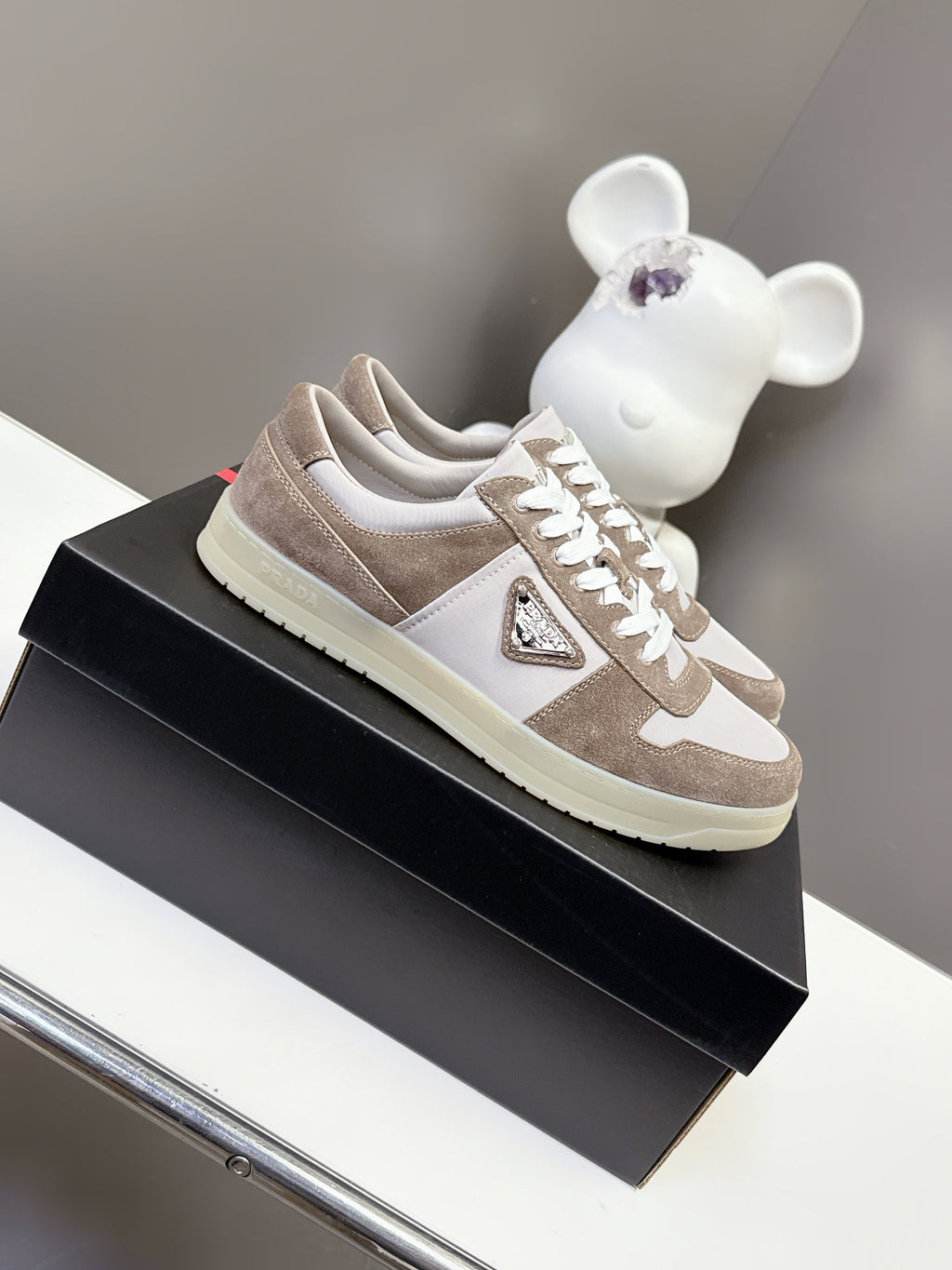Unisex sneakers with suede taupe uppers, white logo, and white lace-up front