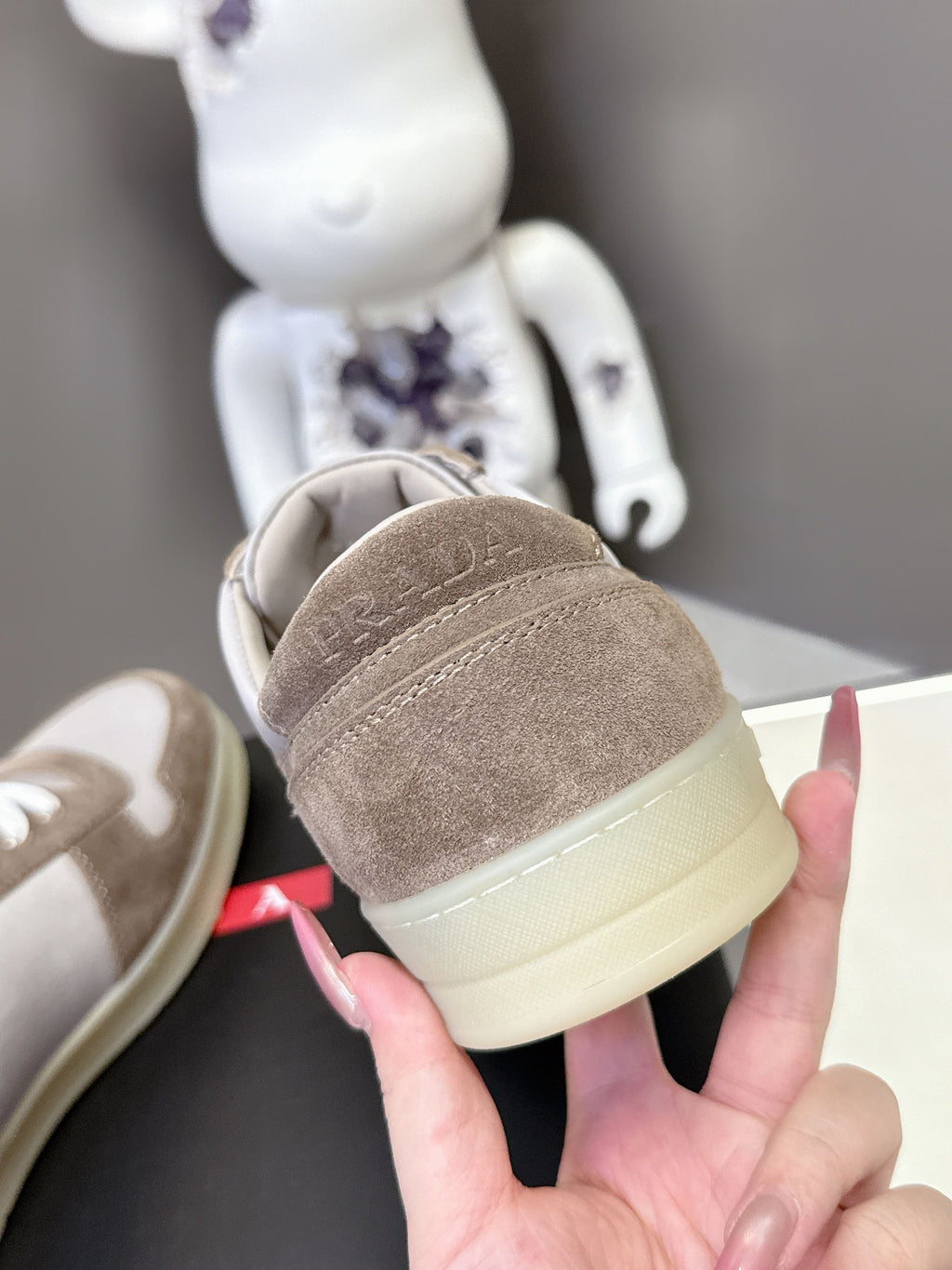 Heel view of taupe suede sneakers with light yellow outsole and white stitching