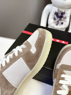 Close-up of taupe suede sneaker side with light yellow sole and white laces