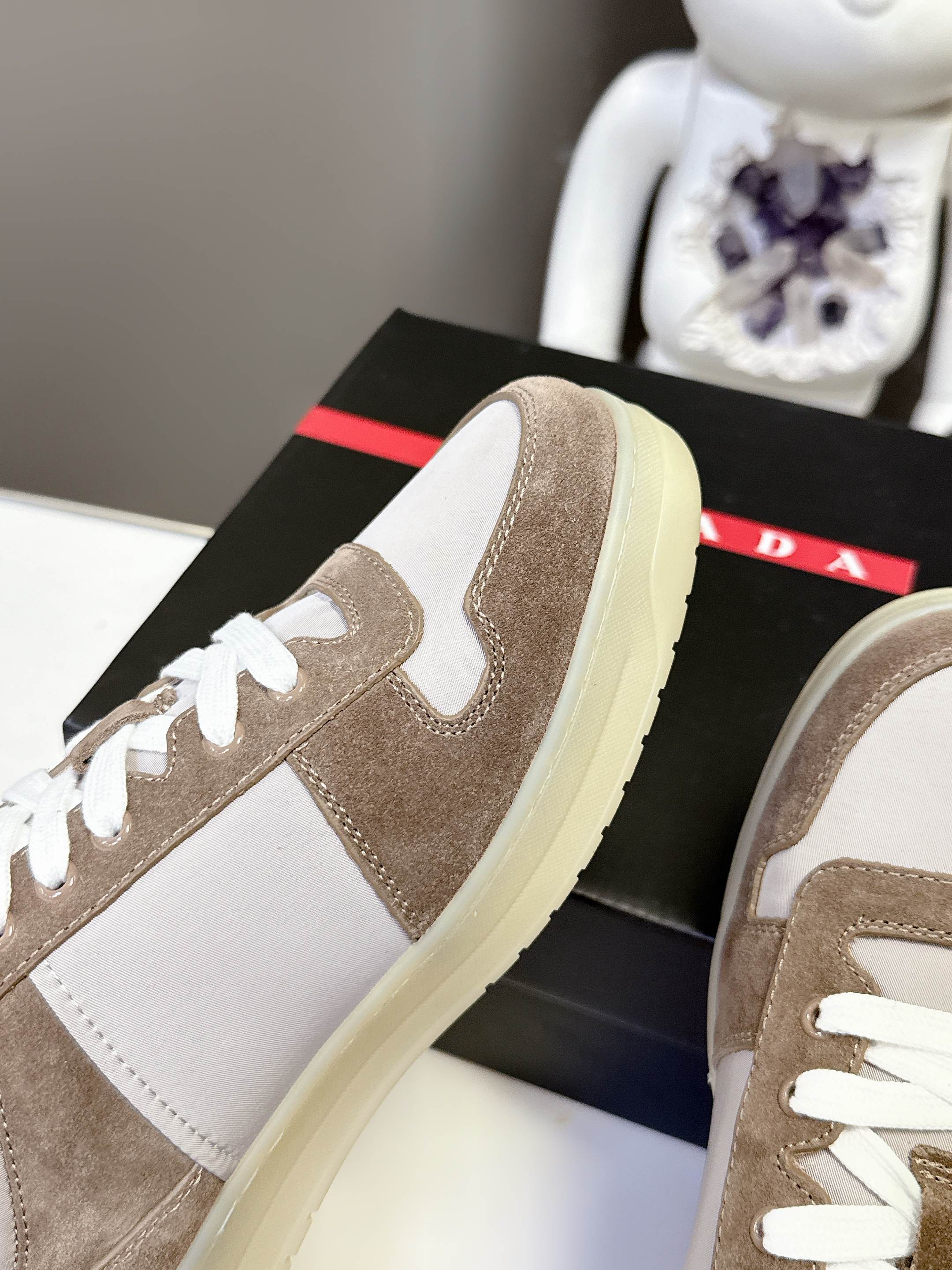 Close-up of taupe suede sneaker side with light yellow sole and white laces