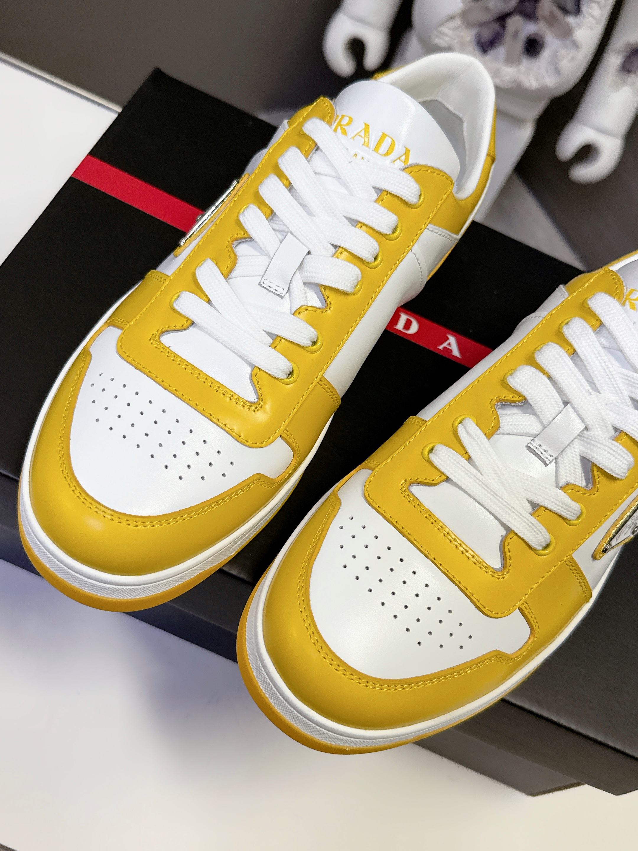 Prada unisex sneakers close-up, yellow leather, white laces, Prada logo on tongue