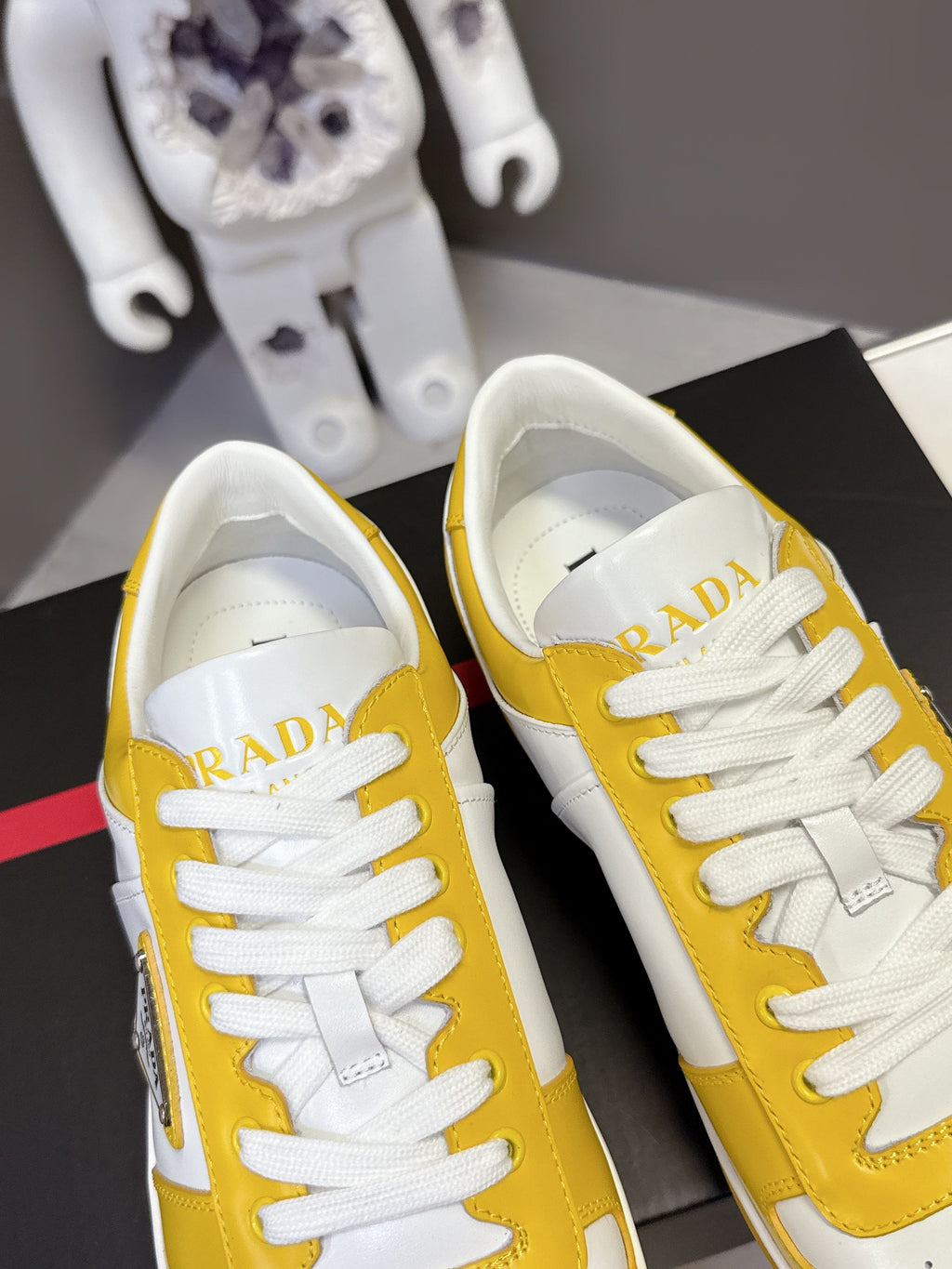 Prada unisex sneakers close-up, white uppers with yellow panels and logo on heel