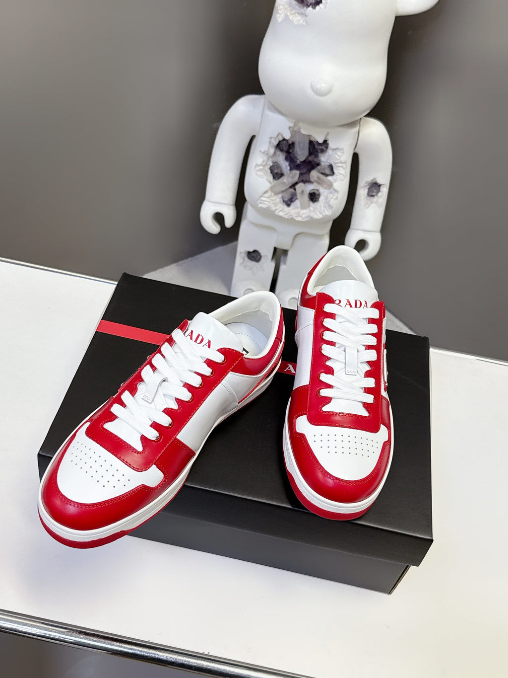 Red and white low-top sneakers with white laces and side logo badge