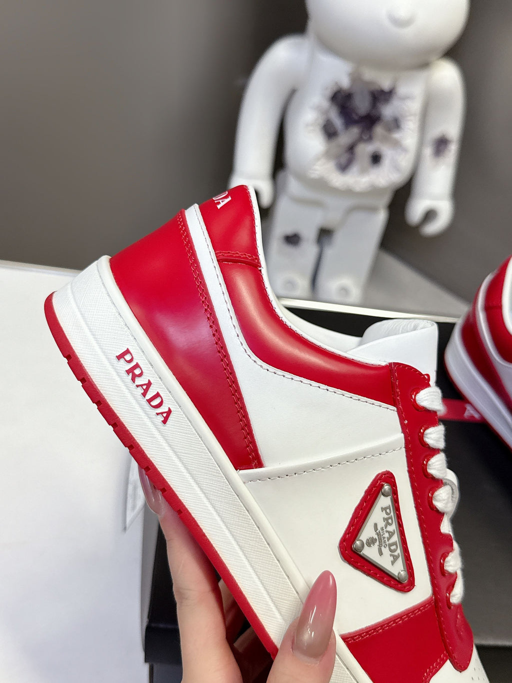 Red and white low-top sneakers with triangular side logo patch