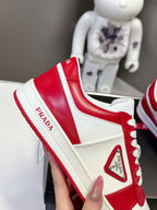 Red and white low-top sneakers with triangular side logo patch