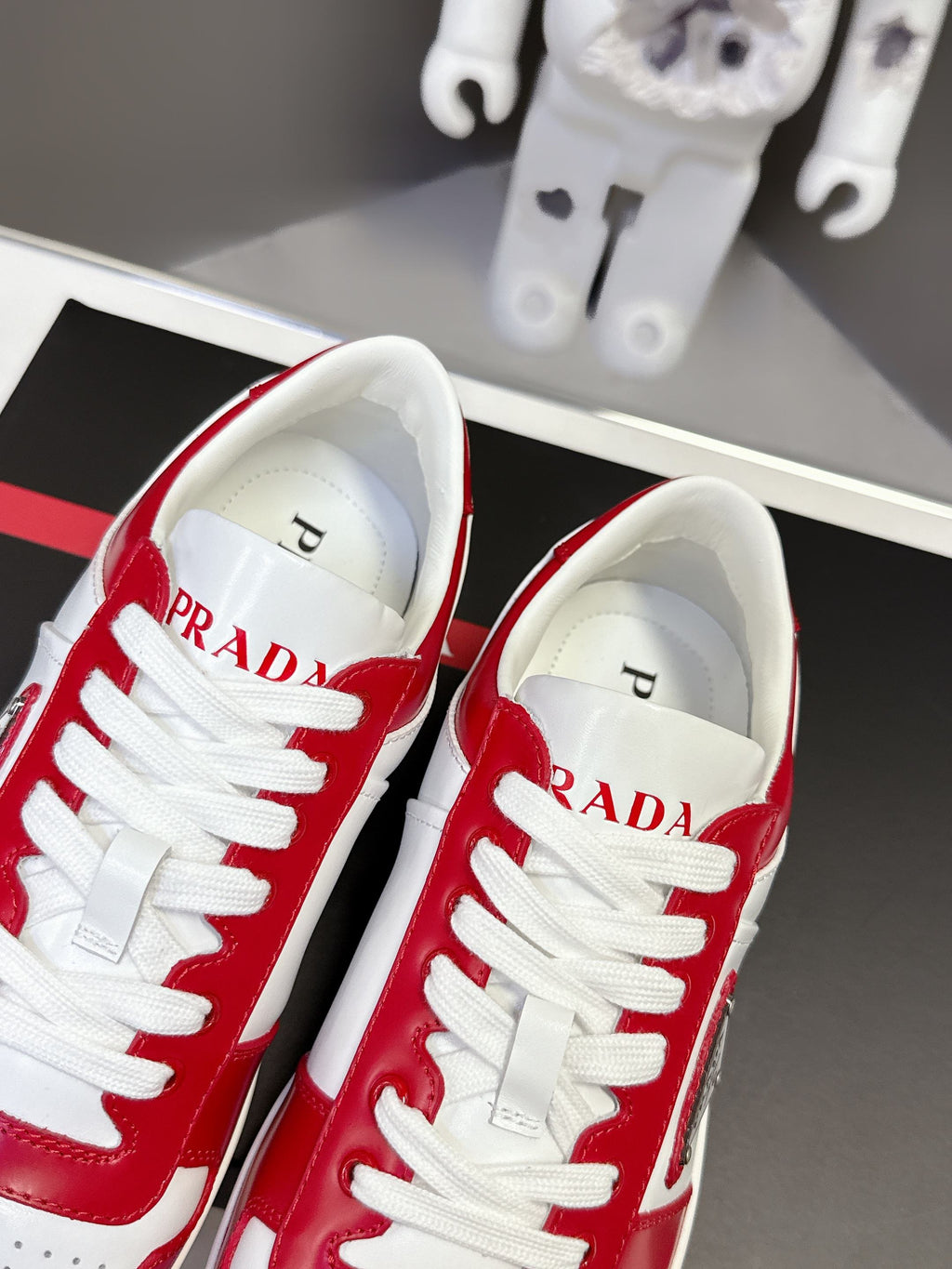 Red and white low-top sneakers with PRADA on the insole