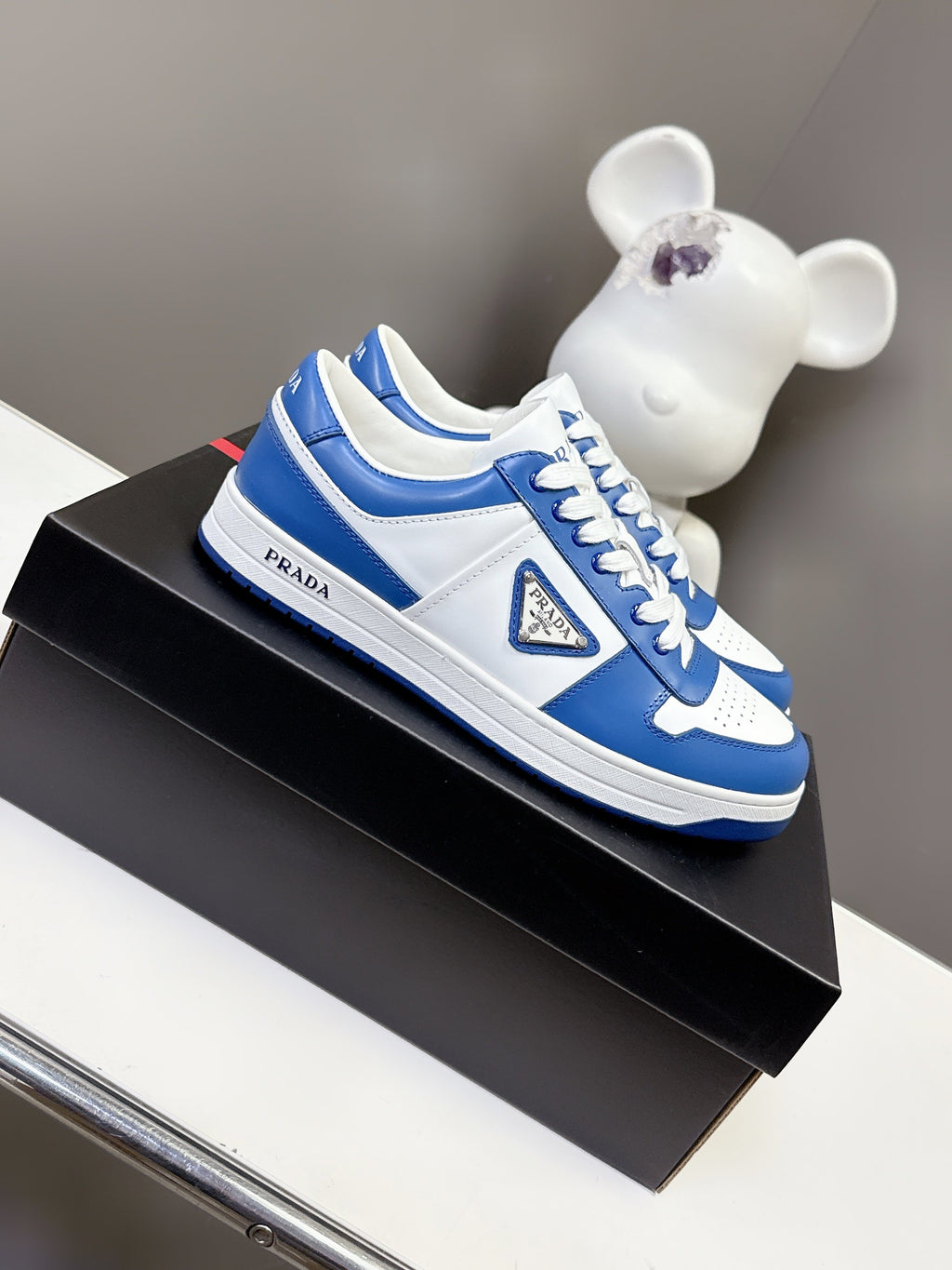 Blue and white Prada sneakers on box, lace-up with side logo patch.