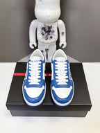 Pair of blue and white lace-up Prada sneakers viewed from front on box.