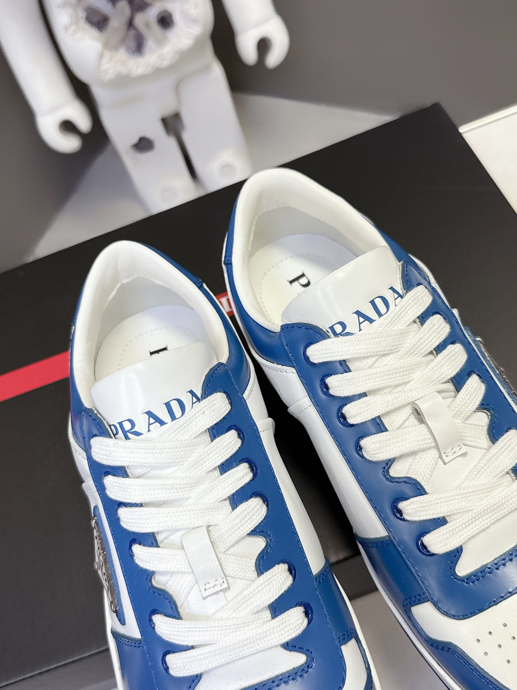 Blue and white Prada sneakers, close toe and tongue view with logo on tongue.