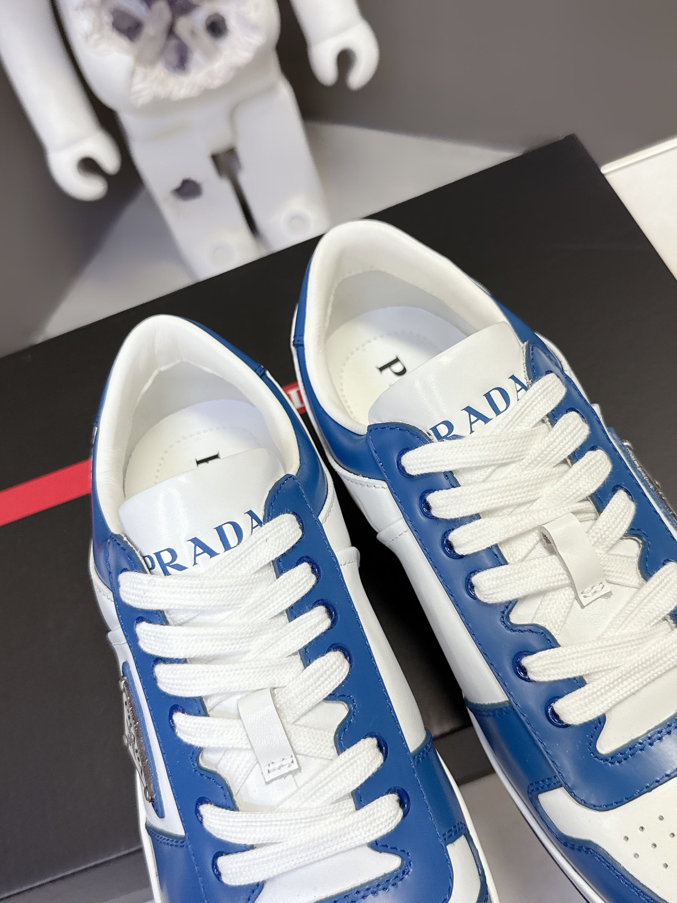Blue and white Prada sneakers, close toe and tongue view with logo on tongue.