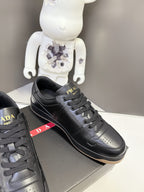 Prada black low-top sneakers with red PRADA side stripe and lace-up design