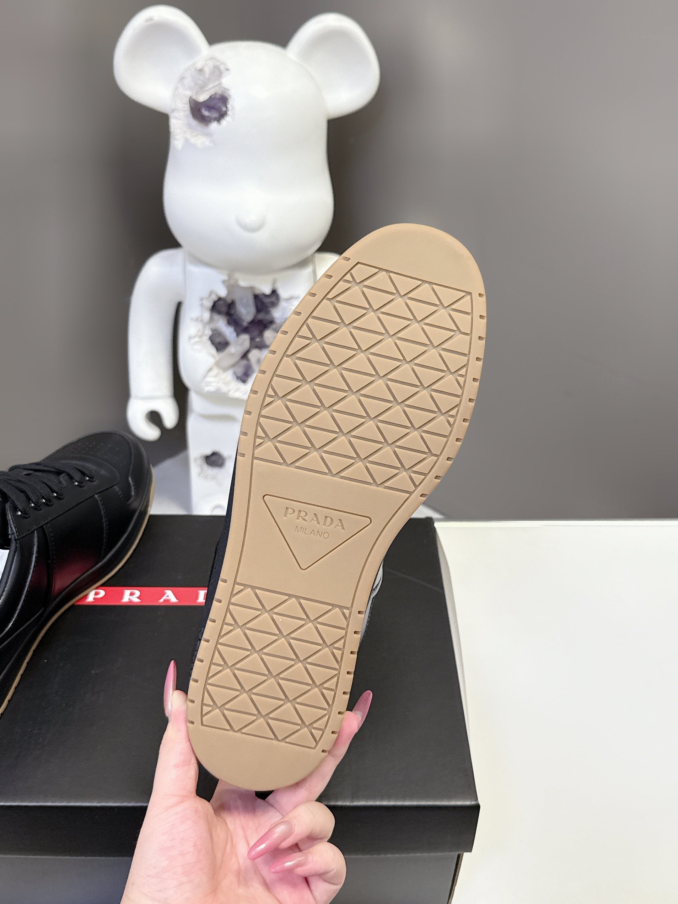 Prada black sneaker outsole with tan tread pattern and PRADA logo