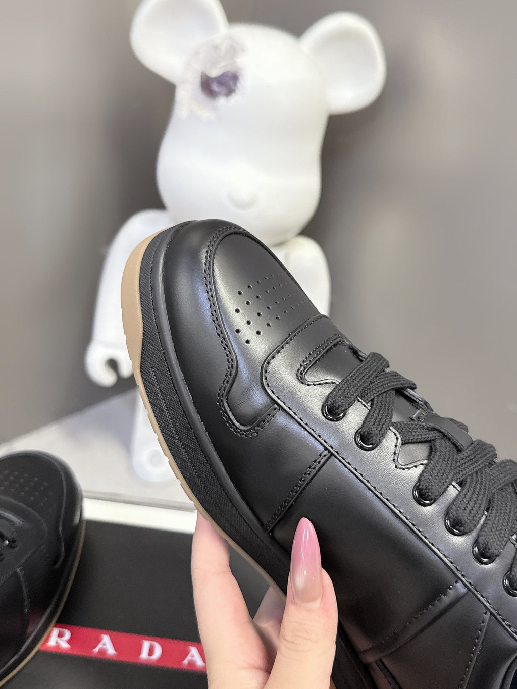 Prada black lace-up sneaker close-up, perforated toe and stitched side panels