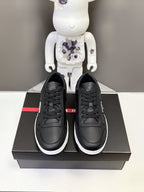 Pair of black Prada unisex lace-up sneakers on a box, with white midsoles