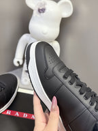 Black Prada unisex sneaker with perforated toe and side swoosh-like logo detail