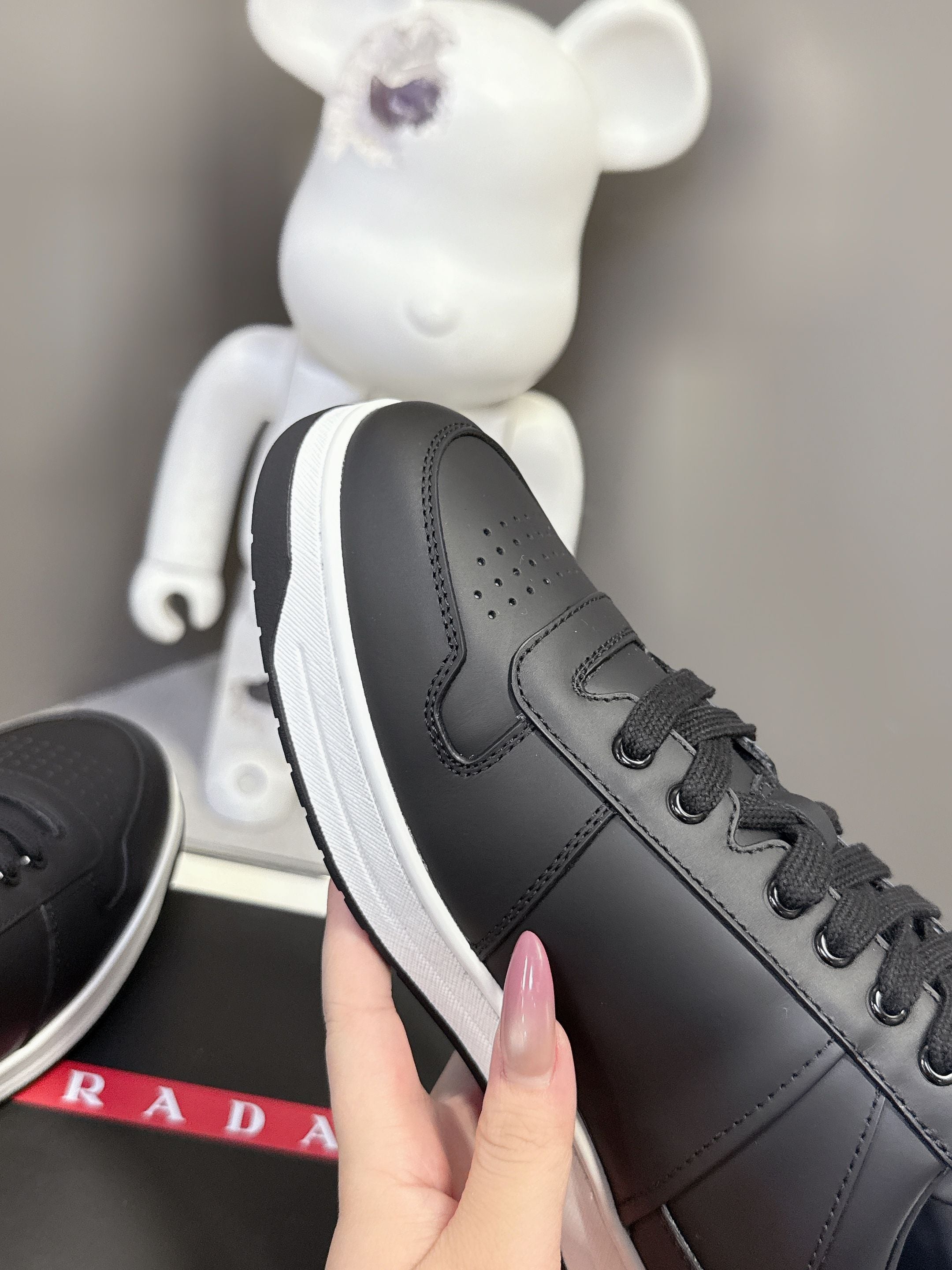 Black Prada unisex sneaker with perforated toe and side swoosh-like logo detail