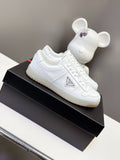 White Prada lace-up sneakers, front view on a black shoe box