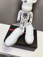 White Prada low-top sneakers with lace-up front, angled on a black box