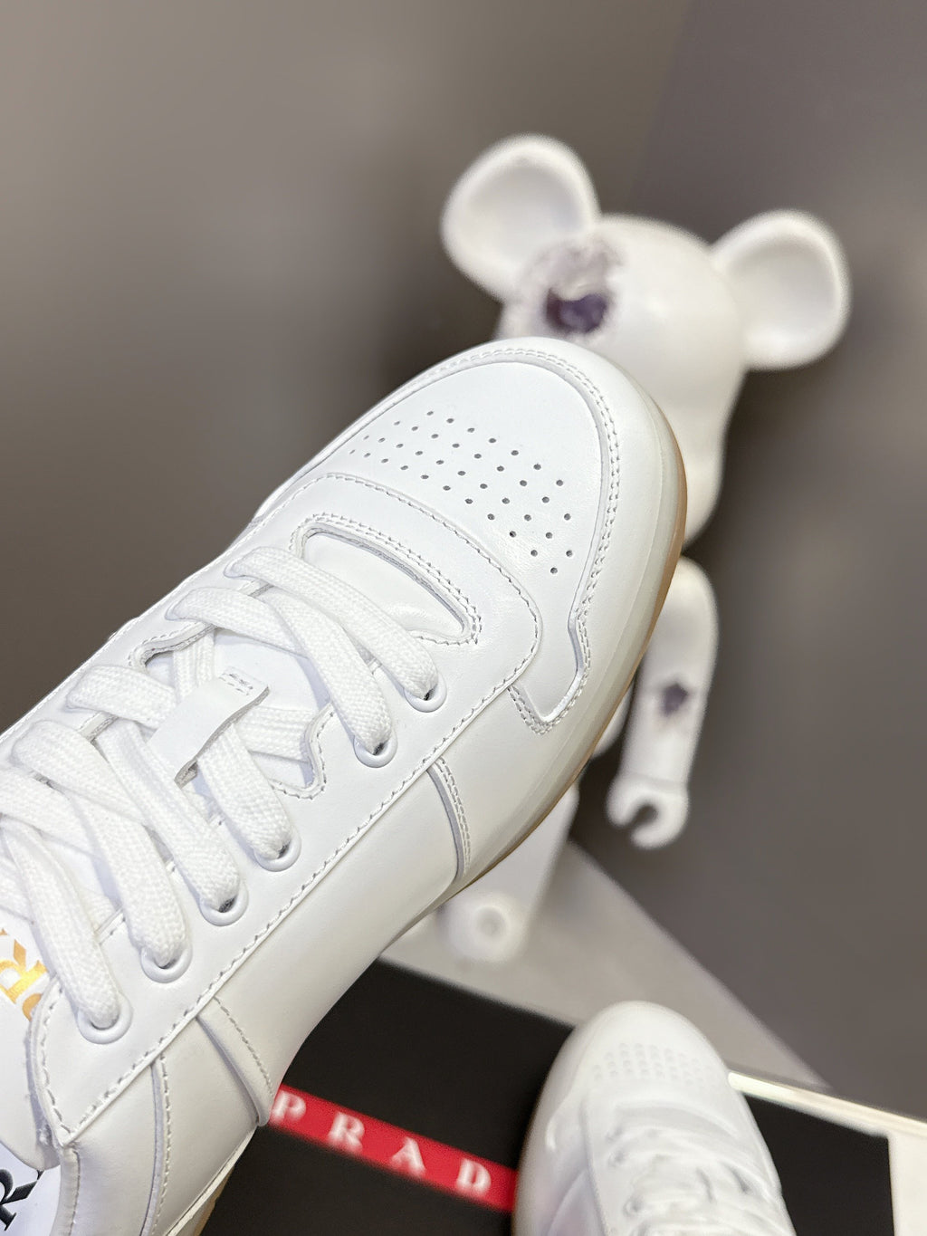 White Prada sneaker close-up of toe perforations and lace-up panel