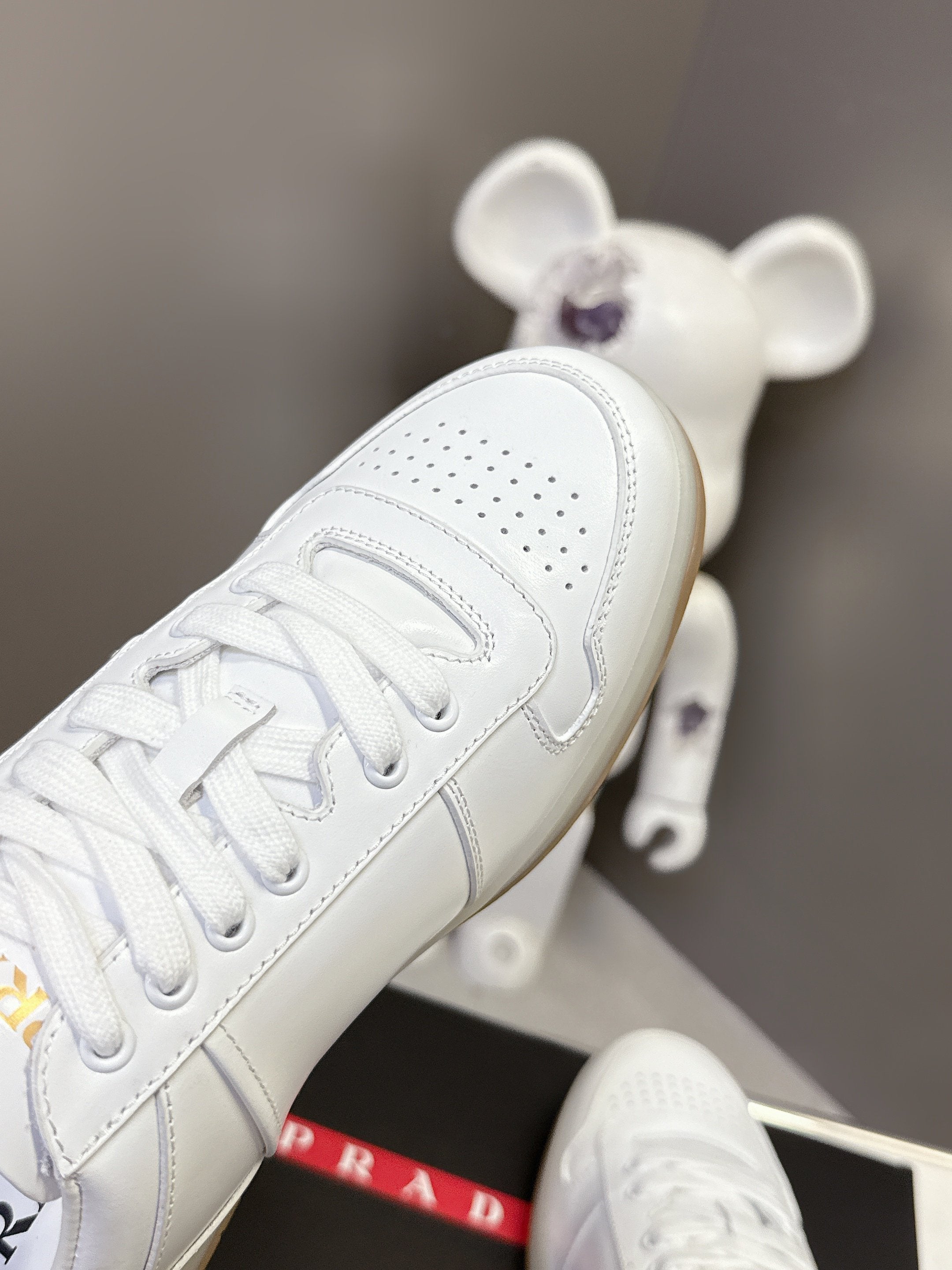 White Prada sneaker close-up of toe perforations and lace-up panel