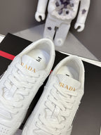 White Prada sneakers close-up of tongue with gold logo on black box