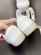 White Prada sneakers close-up at heel with logo on off-white sole