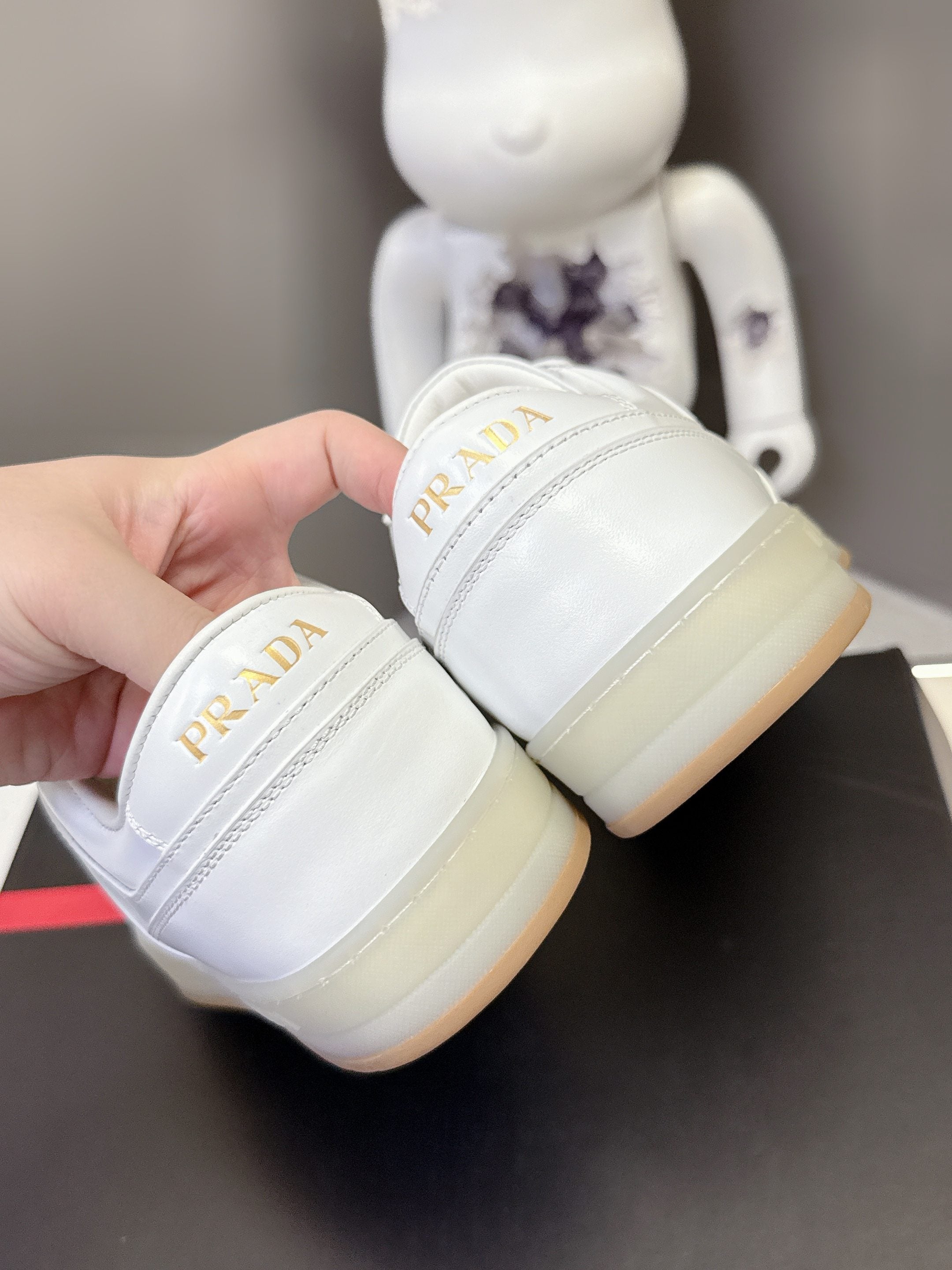 White Prada sneakers close-up at heel with logo on off-white sole