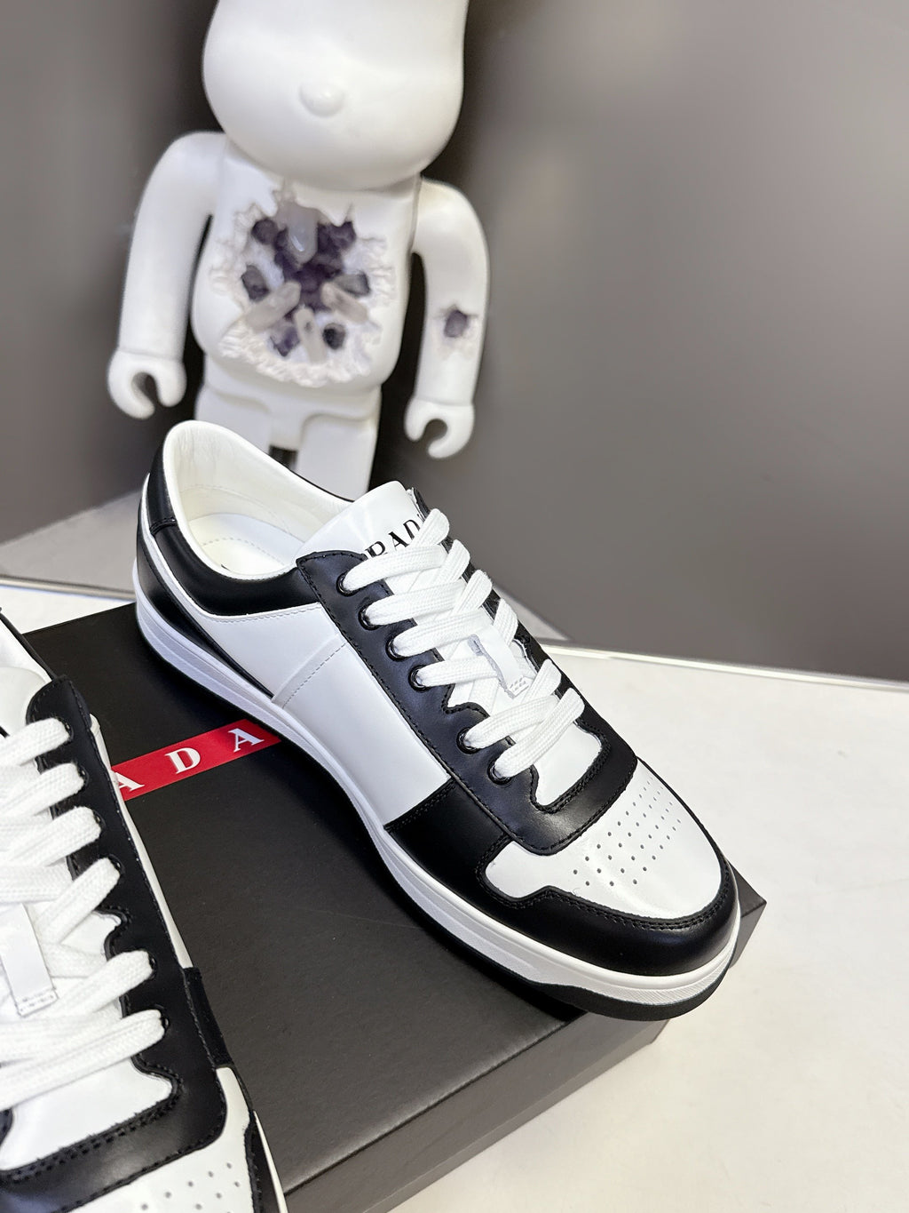 Prada unisex sneakers side view, black leather with white panel and lace overlay