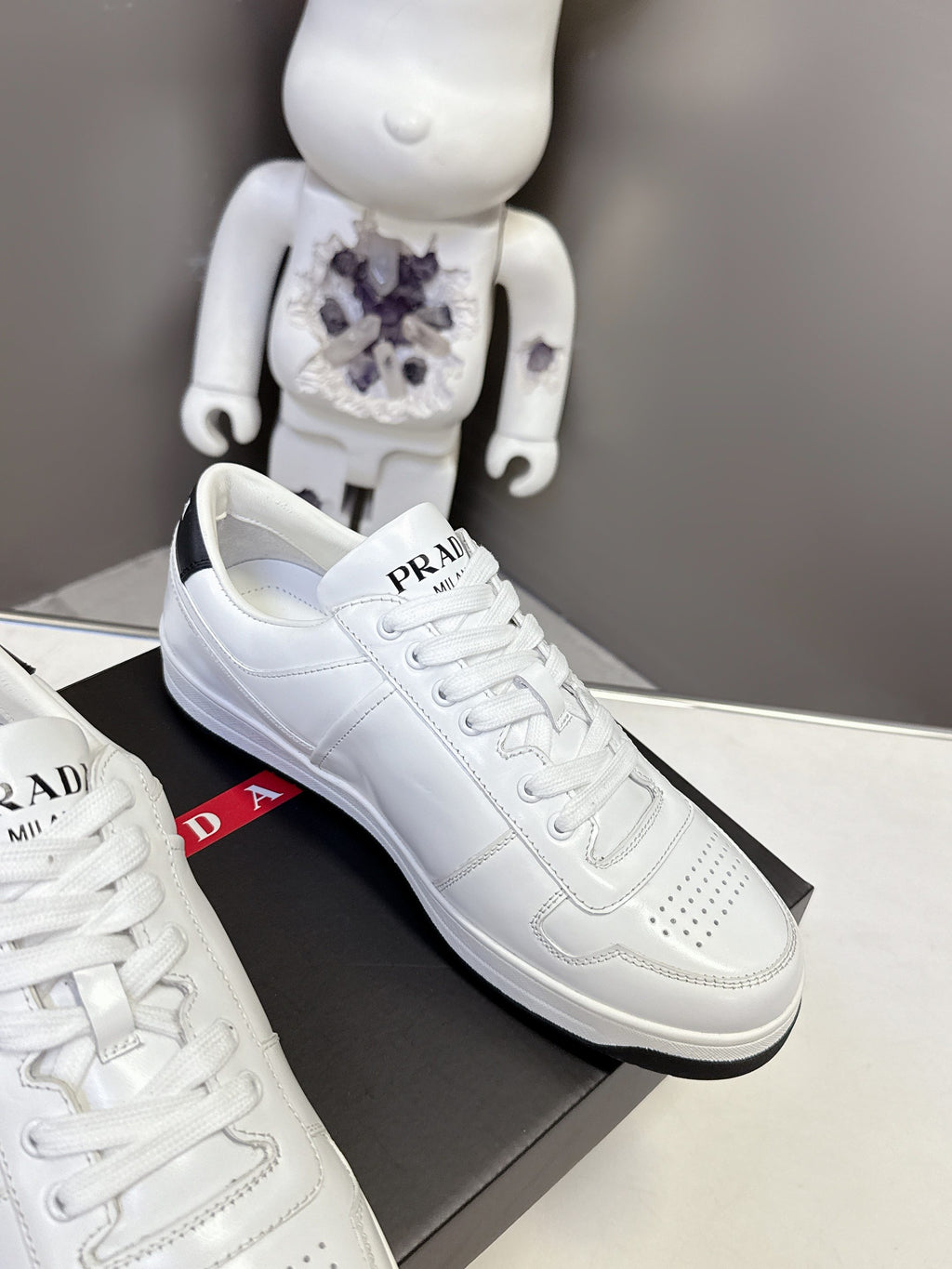 White Prada unisex sneakers side view with PRADA logo on the tongue