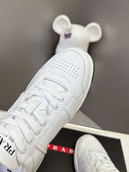 White Prada unisex sneaker angled view with perforated toe and lace-up closure