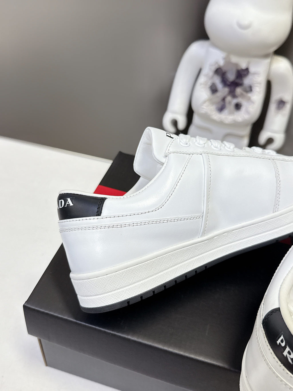 White Prada unisex low-top sneaker with side stripe and black red shoebox base