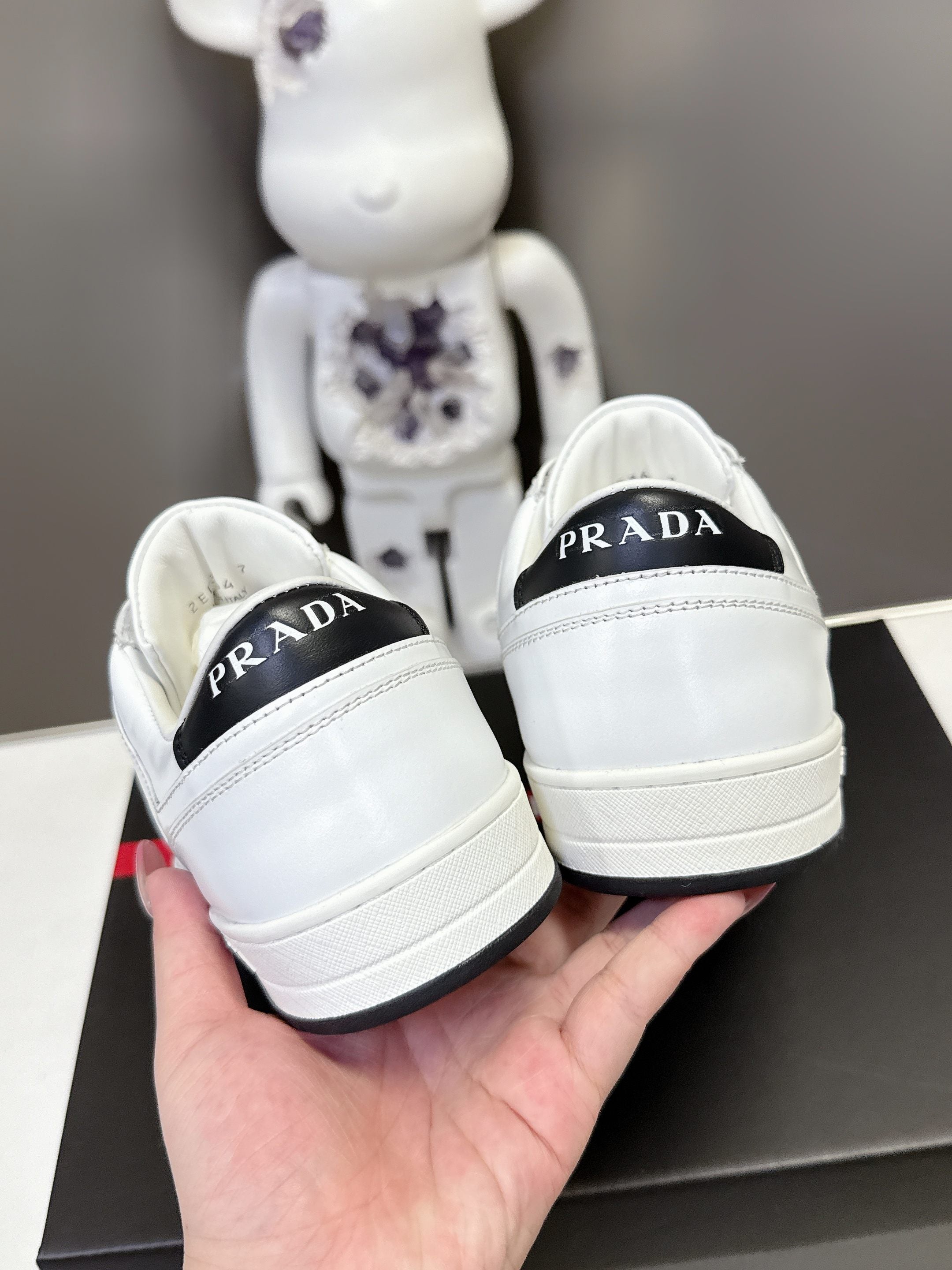 Back view of white Prada unisex sneakers showing heel PRADA logos