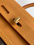 Louis Vuitton men's bag close-up: tan leather strap and gold hardware with eyelet cutout