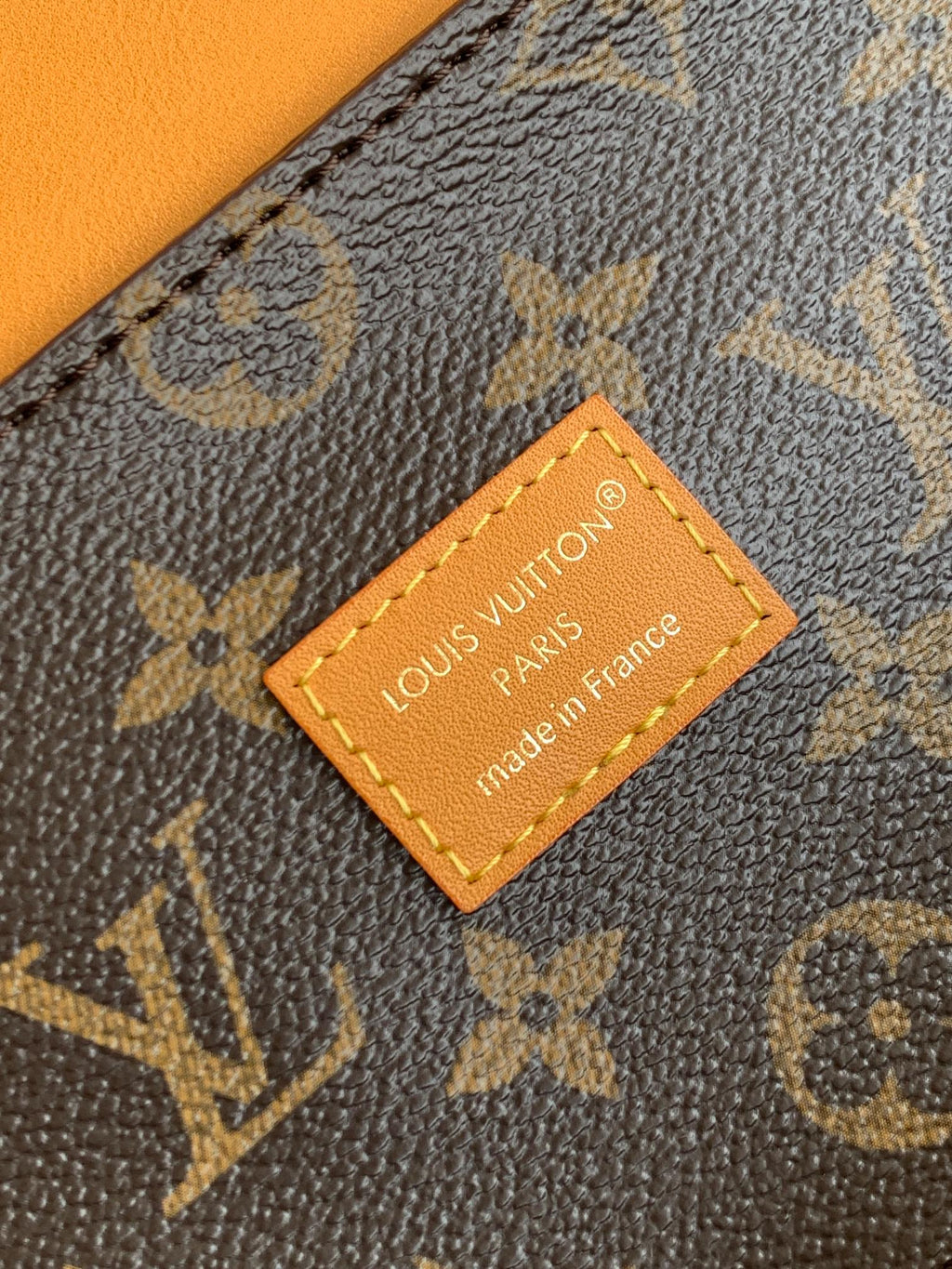 Louis Vuitton monogram bag close-up of tan leather label reading "Louis Vuitton"