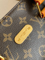 Louis Vuitton men's bag close-up: red-and-tan strap with metal ring on monogram canvas
