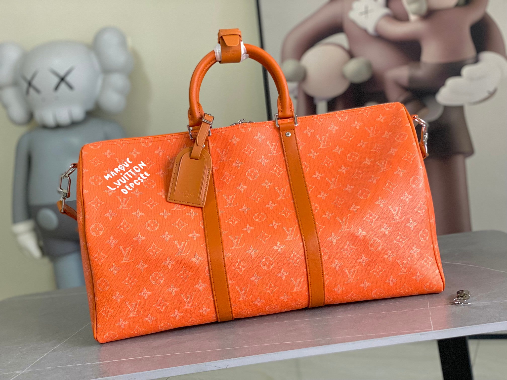 Orange monogram men’s duffel bag with top handles, leather trim, and zip closure.