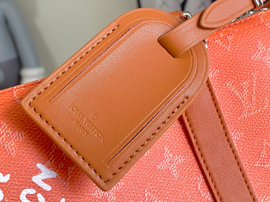 Tan leather strap patch with embossed Louis Vuitton text on orange monogram bag.