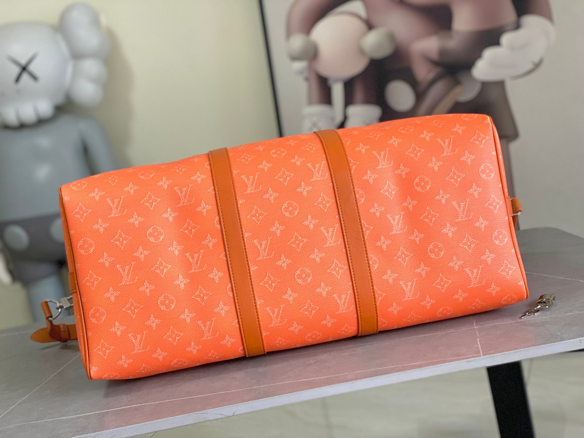 Orange monogram duffel-style bag with long strap and leather accents