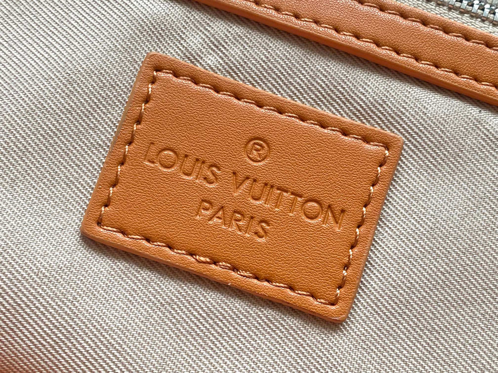 Louis Vuitton fabric label patch reading “Louis Vuitton Paris” on orange bag lining